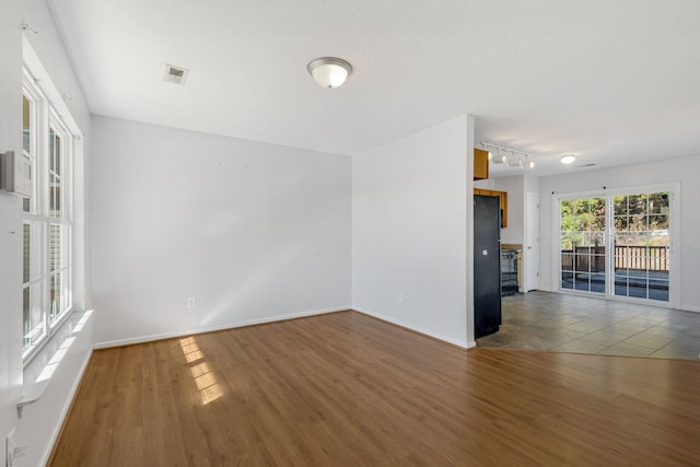 unfurnished living room with a textured ceiling, dark hardwood / wood-style floors, and rail lighting