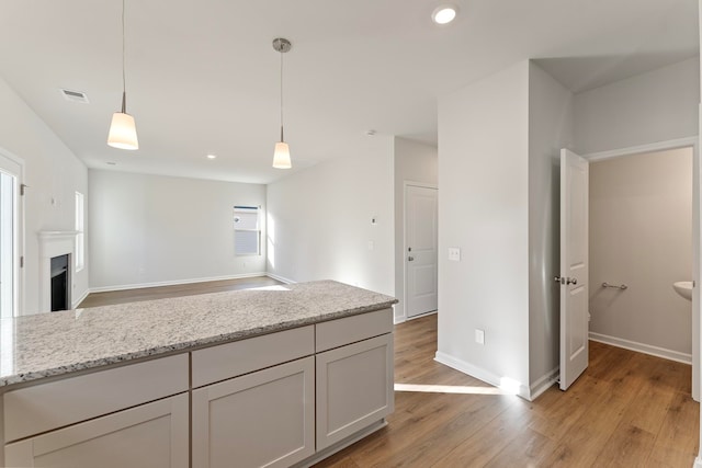 kitchen featuring light stone countertops, light hardwood / wood-style floors, and hanging light fixtures