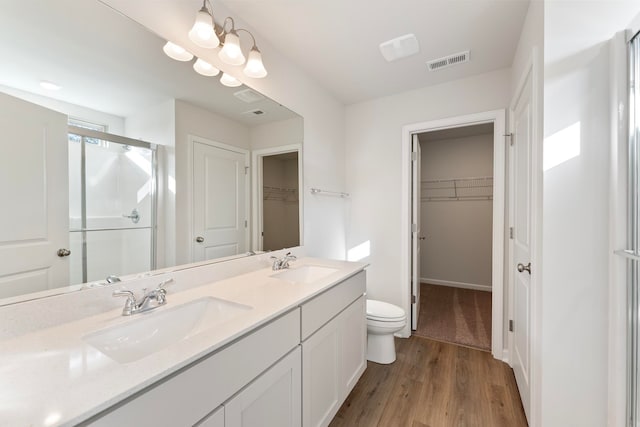 bathroom with toilet, vanity, an enclosed shower, and hardwood / wood-style flooring