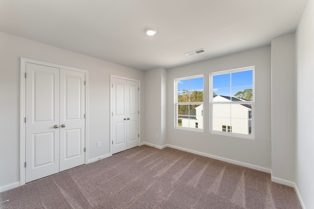 unfurnished bedroom with carpet and multiple closets