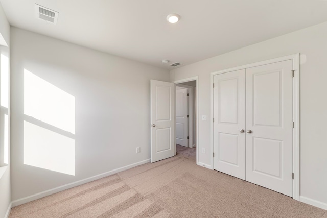 unfurnished bedroom featuring a closet and light colored carpet