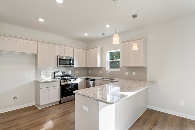 kitchen featuring decorative light fixtures, stainless steel appliances, white cabinetry, and hardwood / wood-style floors