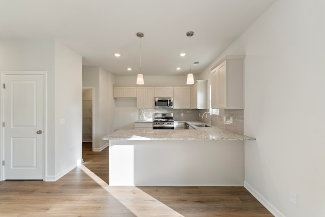 kitchen with sink, hanging light fixtures, light wood-type flooring, and appliances with stainless steel finishes