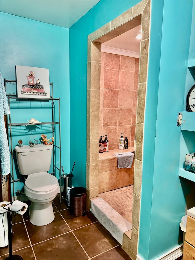 bathroom featuring toilet, a shower, tile patterned floors, and crown molding