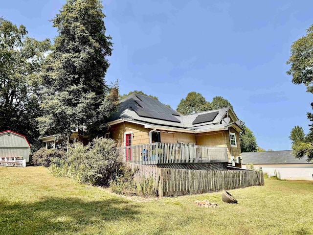 back of property with a storage shed, a yard, and solar panels