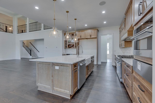 kitchen with light stone countertops, appliances with stainless steel finishes, dark hardwood / wood-style flooring, hanging light fixtures, and an island with sink