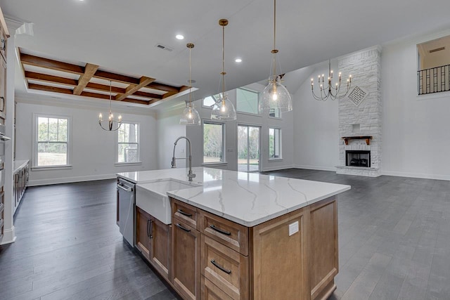 kitchen with coffered ceiling, a large island with sink, a fireplace, dark hardwood / wood-style floors, and hanging light fixtures