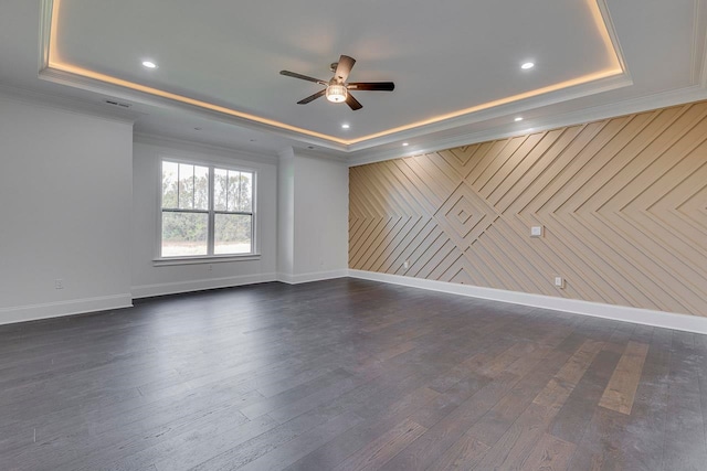 empty room featuring dark hardwood / wood-style flooring, a tray ceiling, ceiling fan, and wood walls