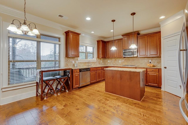 kitchen with a center island, light hardwood / wood-style flooring, decorative light fixtures, and appliances with stainless steel finishes