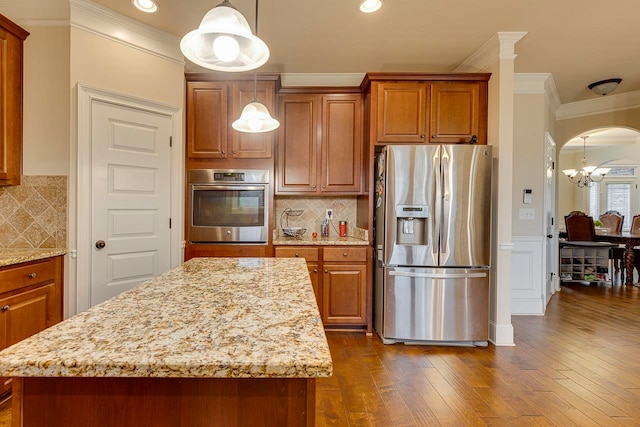 kitchen with backsplash, stainless steel appliances, dark wood-type flooring, decorative light fixtures, and a kitchen island