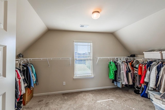 spacious closet with light colored carpet and vaulted ceiling