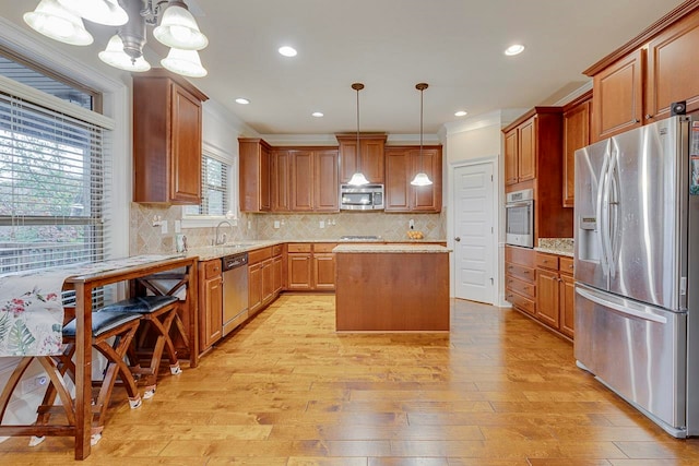 kitchen with tasteful backsplash, stainless steel appliances, decorative light fixtures, light hardwood / wood-style flooring, and a center island