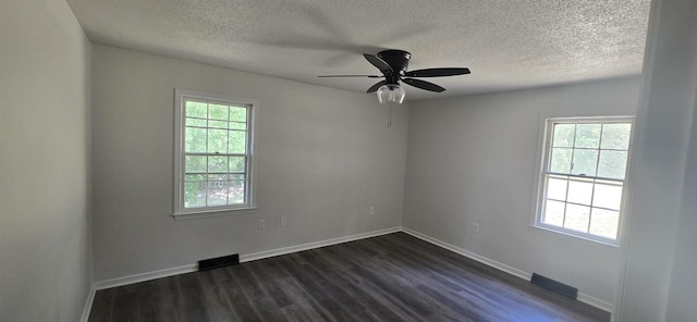 unfurnished room with a healthy amount of sunlight, a textured ceiling, and dark wood-type flooring