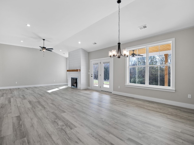 unfurnished living room featuring a fireplace, light hardwood / wood-style flooring, ceiling fan with notable chandelier, and lofted ceiling