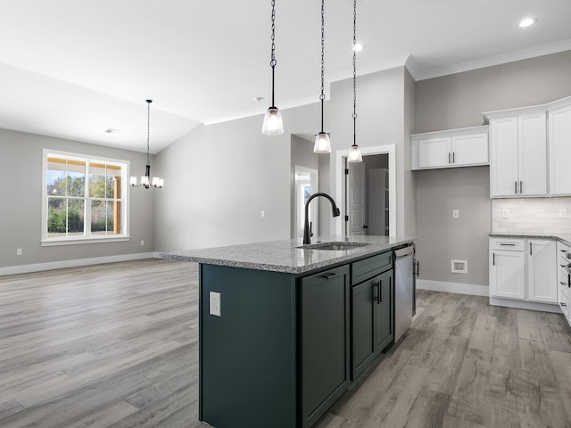 kitchen featuring a kitchen island with sink, sink, hanging light fixtures, light hardwood / wood-style flooring, and light stone counters