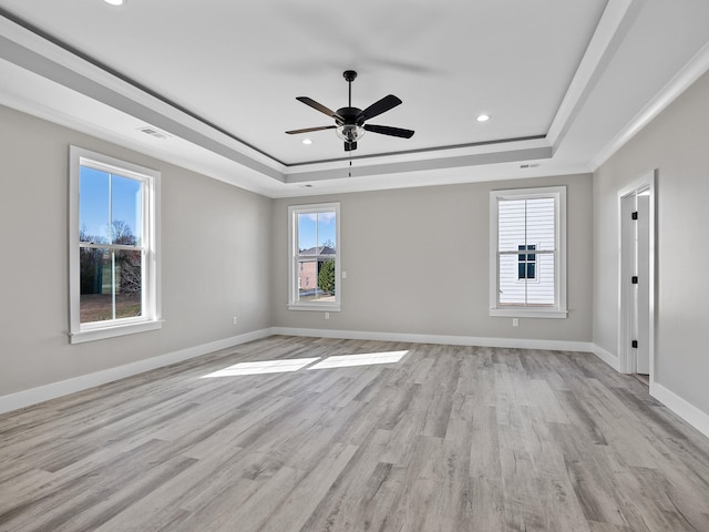 spare room featuring a tray ceiling, light hardwood / wood-style flooring, and ceiling fan