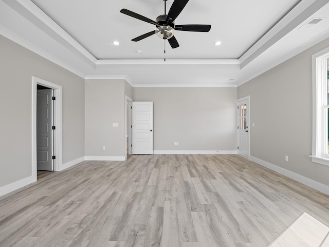 empty room featuring ceiling fan, crown molding, a tray ceiling, and light hardwood / wood-style flooring