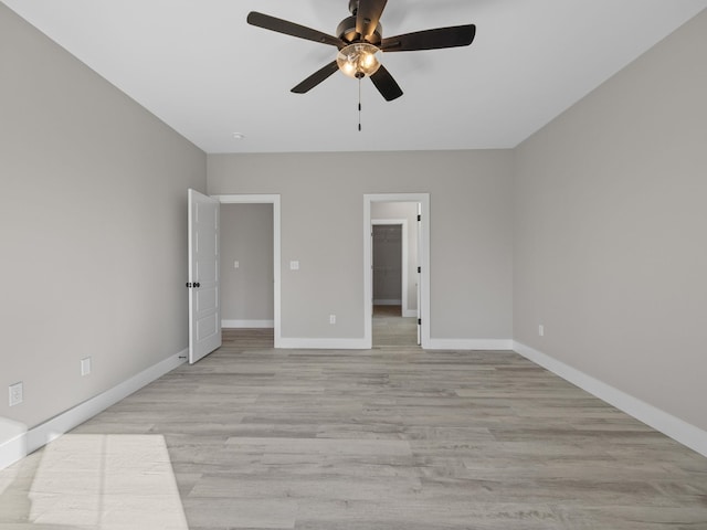 unfurnished bedroom featuring ceiling fan, a walk in closet, and light wood-type flooring