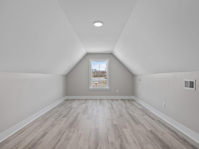 additional living space with vaulted ceiling and light hardwood / wood-style flooring