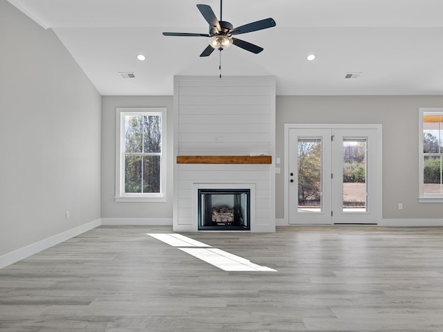 unfurnished living room with a fireplace, light wood-type flooring, ceiling fan, and lofted ceiling