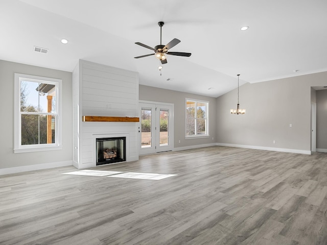 unfurnished living room featuring a fireplace, ceiling fan with notable chandelier, vaulted ceiling, and light wood-type flooring