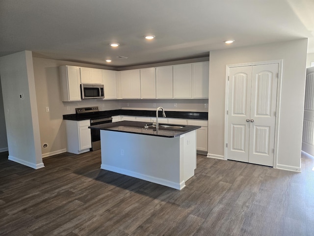 kitchen with appliances with stainless steel finishes, dark wood-type flooring, sink, white cabinetry, and an island with sink