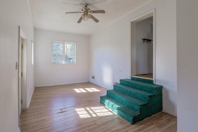 sitting room featuring ceiling fan, light hardwood / wood-style floors, and a textured ceiling