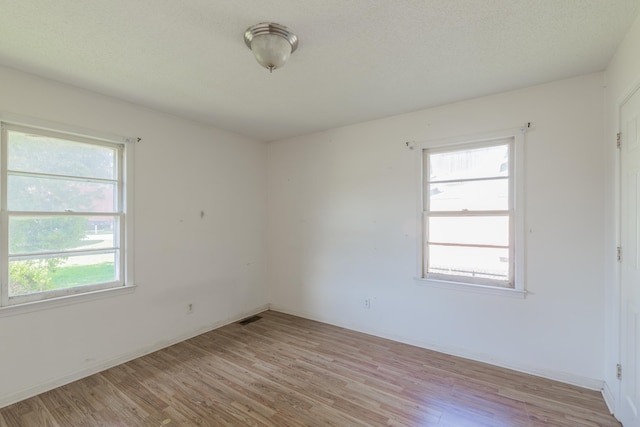 spare room featuring light hardwood / wood-style floors and a textured ceiling