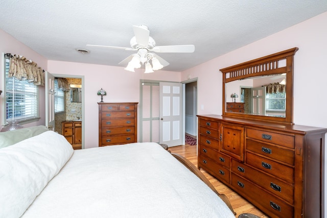 bedroom featuring ensuite bathroom, a textured ceiling, ceiling fan, and a closet