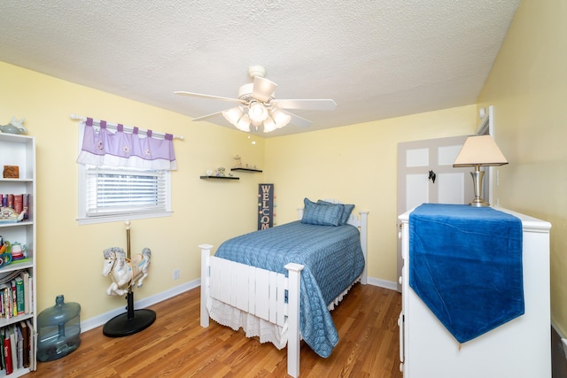 bedroom featuring ceiling fan, hardwood / wood-style floors, and a textured ceiling