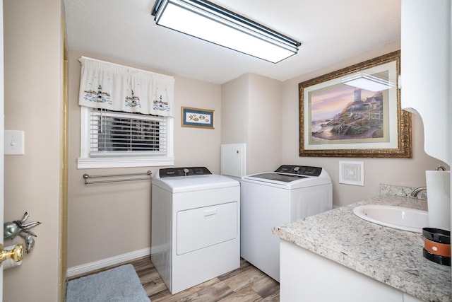 laundry room with washer and clothes dryer, sink, and light hardwood / wood-style flooring