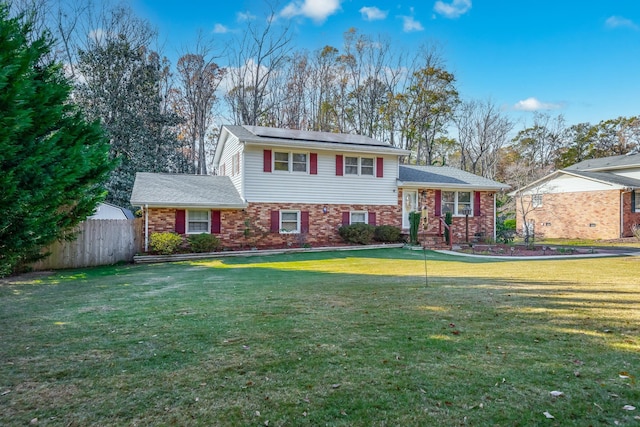 split level home featuring a front lawn and solar panels