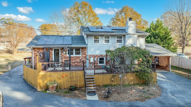 rear view of property with a porch and solar panels