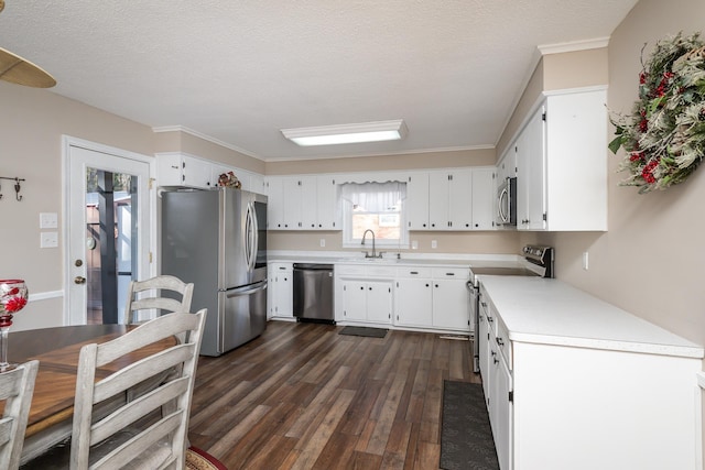 kitchen with sink, appliances with stainless steel finishes, white cabinetry, dark hardwood / wood-style floors, and a textured ceiling