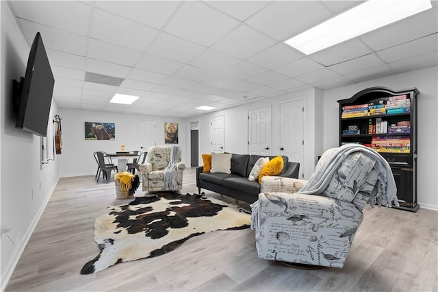 living room with a drop ceiling and light hardwood / wood-style floors