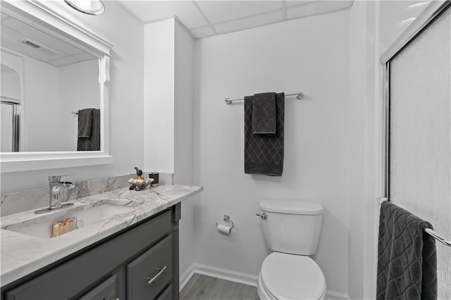 bathroom featuring vanity, a drop ceiling, hardwood / wood-style flooring, toilet, and an enclosed shower