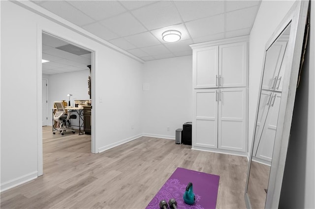 interior space featuring a paneled ceiling and light hardwood / wood-style floors