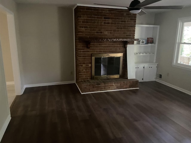 unfurnished living room featuring dark hardwood / wood-style floors, ceiling fan, and a brick fireplace