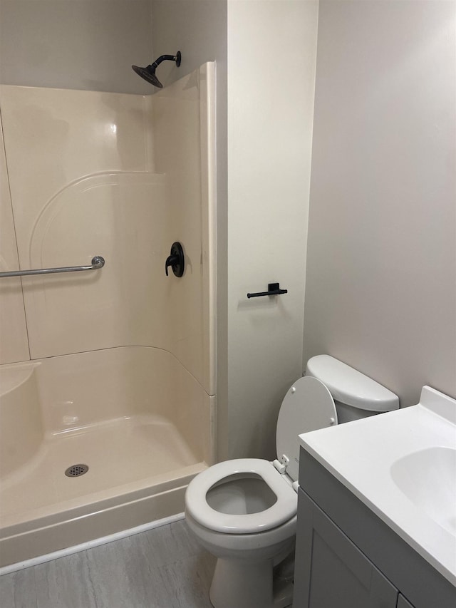 bathroom with hardwood / wood-style flooring, vanity, toilet, and walk in shower