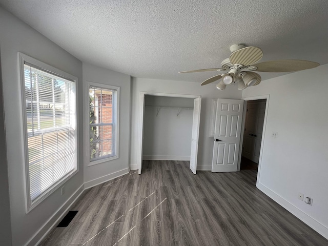 unfurnished bedroom featuring a textured ceiling, ceiling fan, a closet, and dark hardwood / wood-style floors