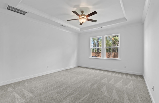 carpeted spare room featuring ceiling fan, ornamental molding, and a raised ceiling