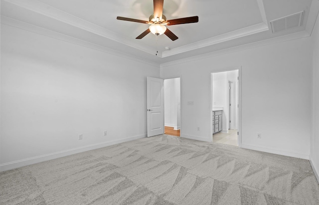 unfurnished bedroom featuring light carpet, ornamental molding, a raised ceiling, ceiling fan, and ensuite bathroom