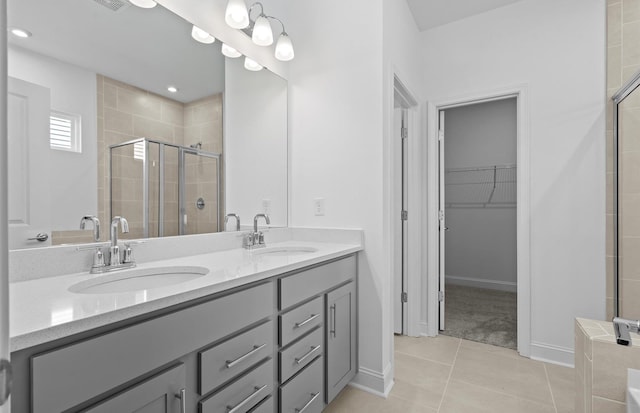 bathroom with a shower with door, vanity, and tile patterned flooring