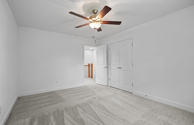 unfurnished bedroom featuring ceiling fan, light colored carpet, and a closet