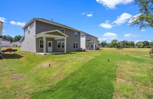 rear view of property featuring a lawn and a patio area