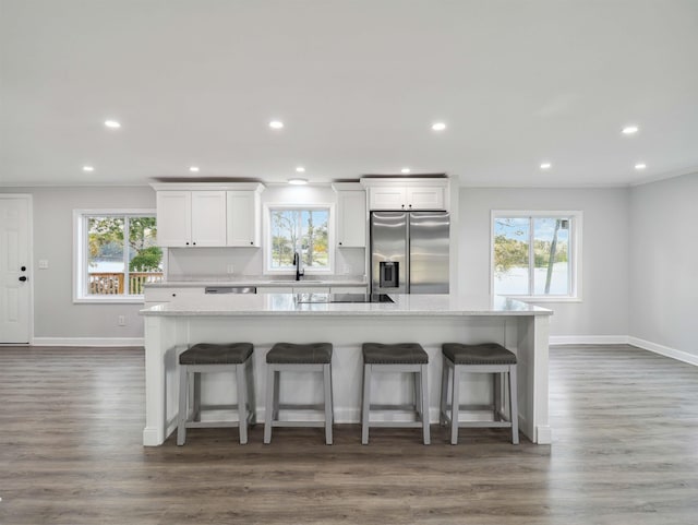 kitchen with white cabinets, stainless steel fridge, a kitchen breakfast bar, and a healthy amount of sunlight