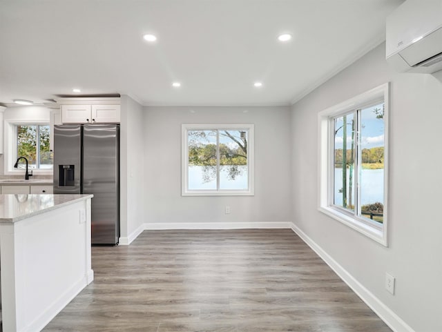 kitchen with stainless steel fridge with ice dispenser, white cabinets, and a healthy amount of sunlight