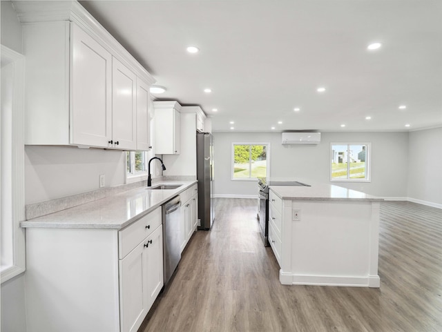 kitchen featuring a wall mounted air conditioner, light stone countertops, light hardwood / wood-style floors, white cabinetry, and stainless steel appliances