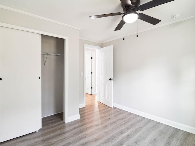 unfurnished bedroom featuring ceiling fan, light wood-type flooring, crown molding, and a closet