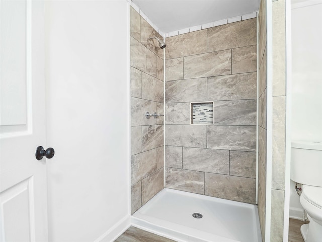 bathroom featuring tiled shower, wood-type flooring, and toilet